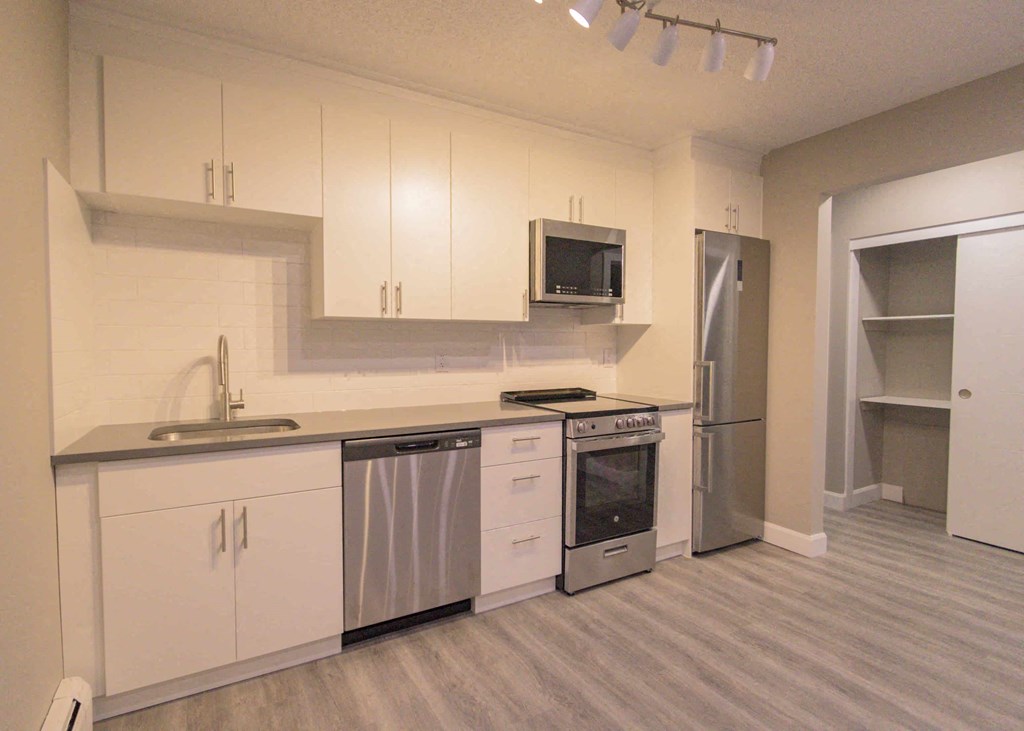 a kitchen with white cabinets and stainless steel appliances