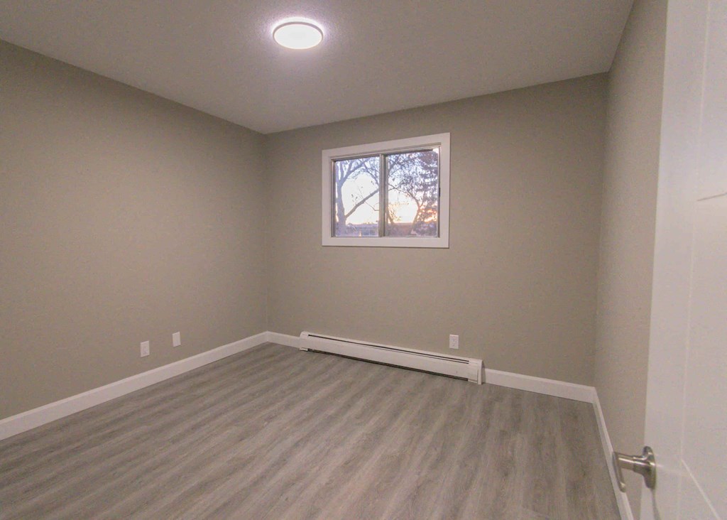 an empty room with wooden floors and a window