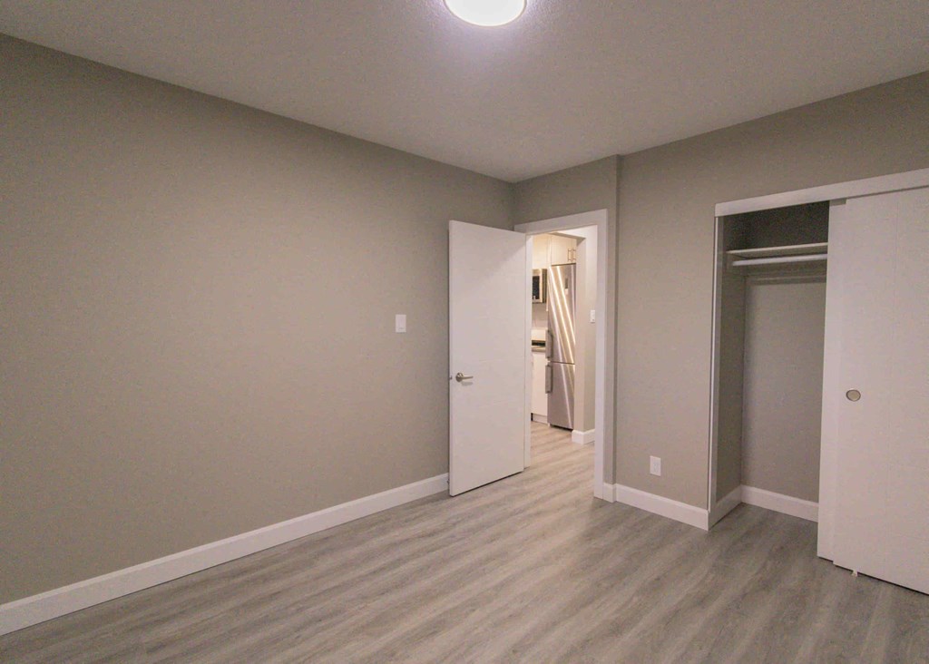 an empty room with a door to a hallway and a closet