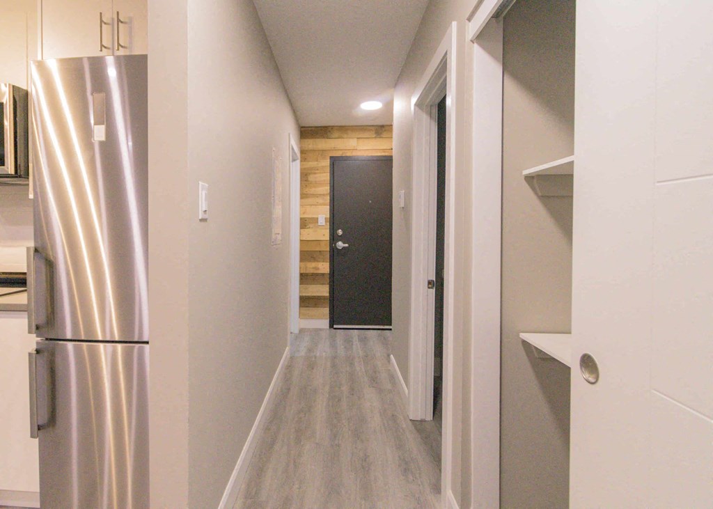 a long hallway with a refrigerator and a black door