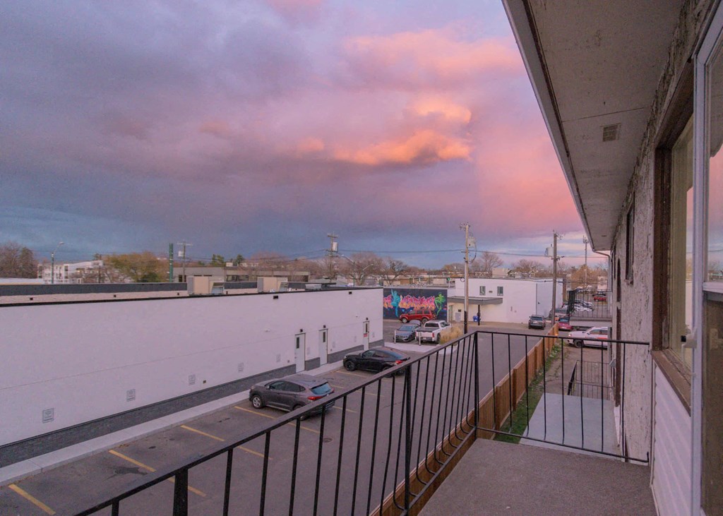 a balcony with a view of a parking lot and a cloudy sky