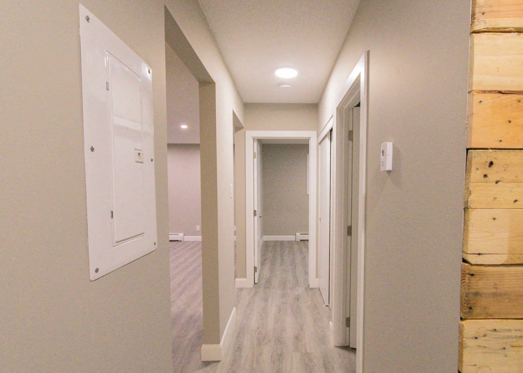a long hallway with white doors and wood floors