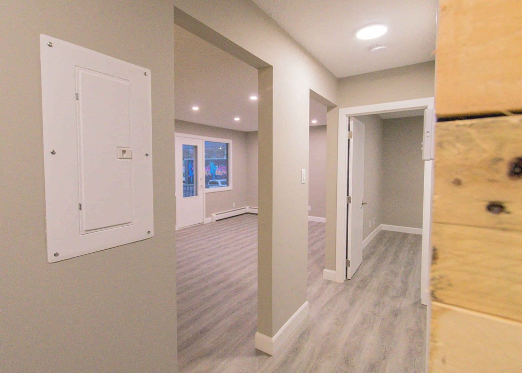 a newly renovated living room and hallway with a door to a bedroom