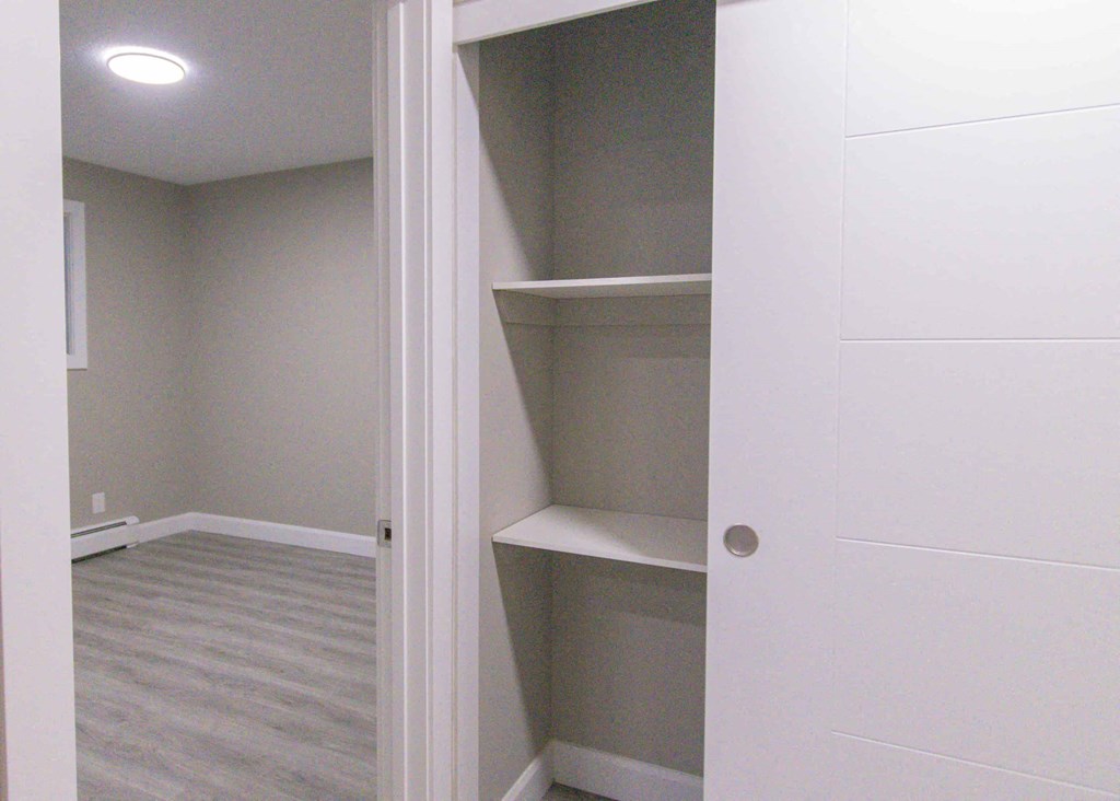 a closet with white shelves and a white door