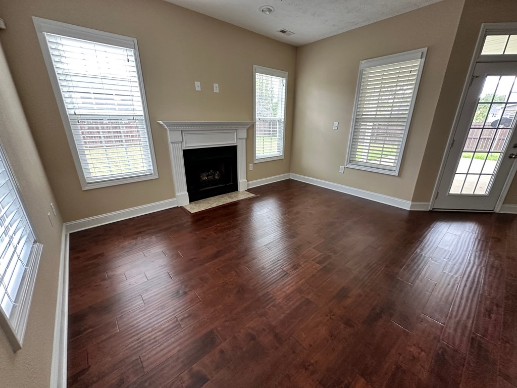 an empty living room with wooden floors and a fireplace