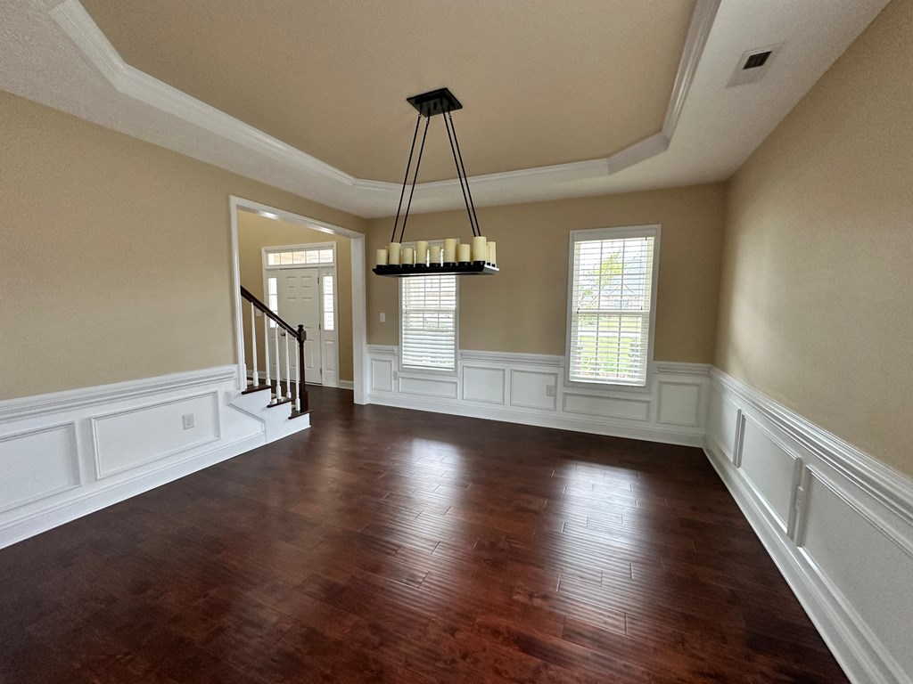 an empty living room with wood floors and a chandelier