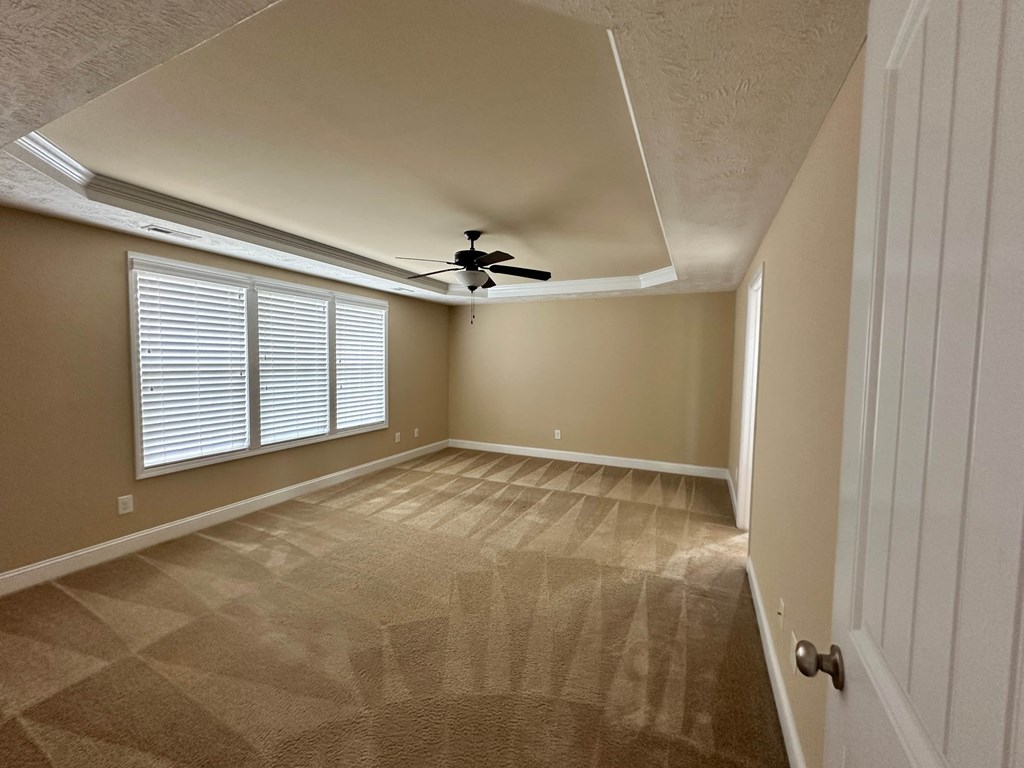 the spacious living room has a ceiling fan and a large window