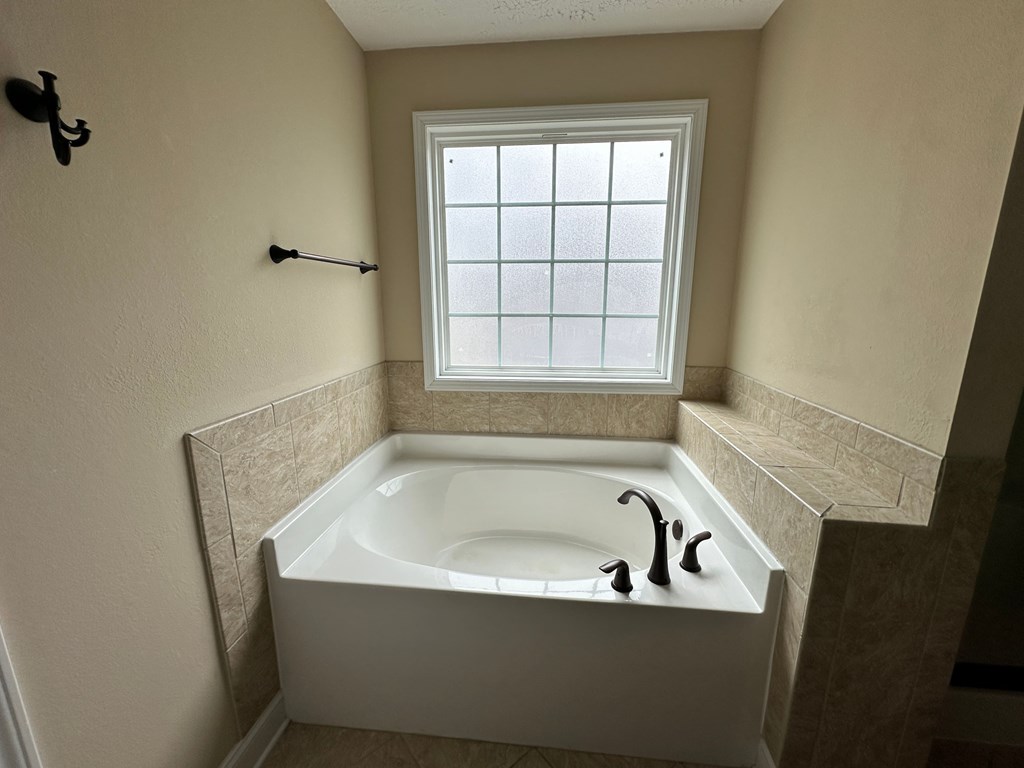 the master bathroom has a large soaking tub and a window