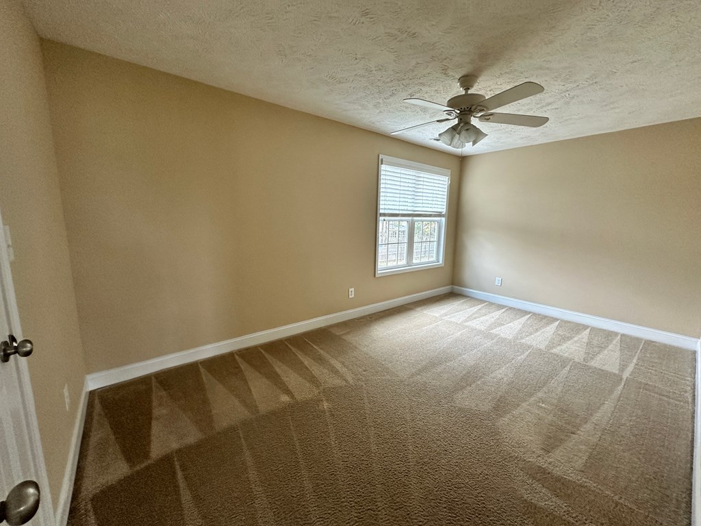 an empty living room with a ceiling fan