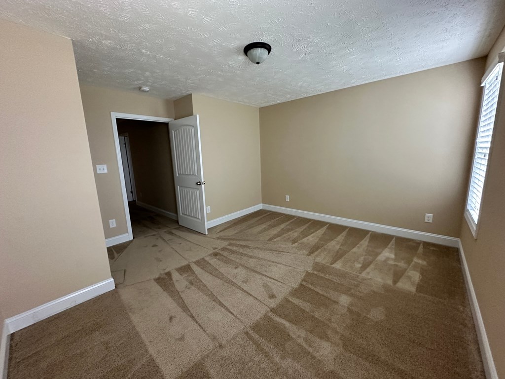 a empty living room with carpet and a door to a hallway