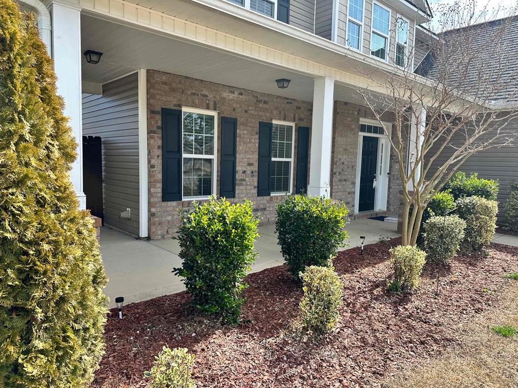 a front porch of a house with bushes and shrubs