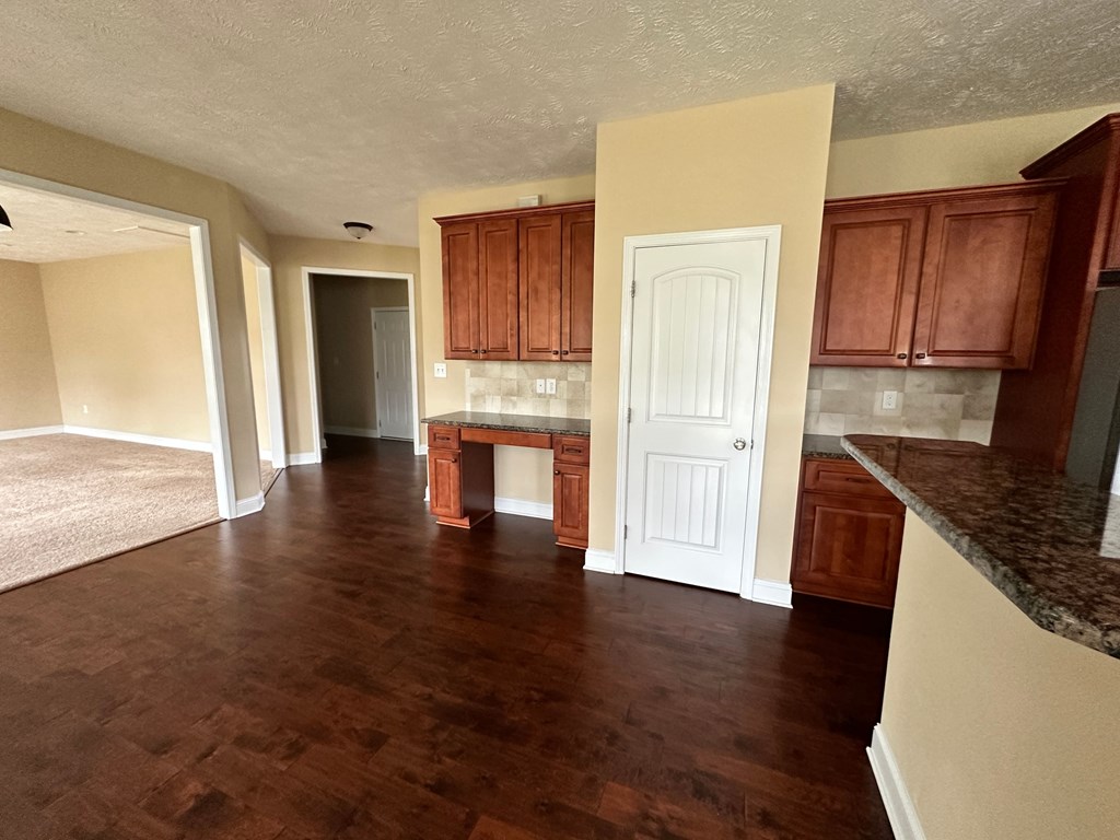 an empty kitchen and living room with wooden floors and cabinets