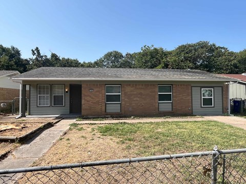 a brick house with a yard and a chain link fence