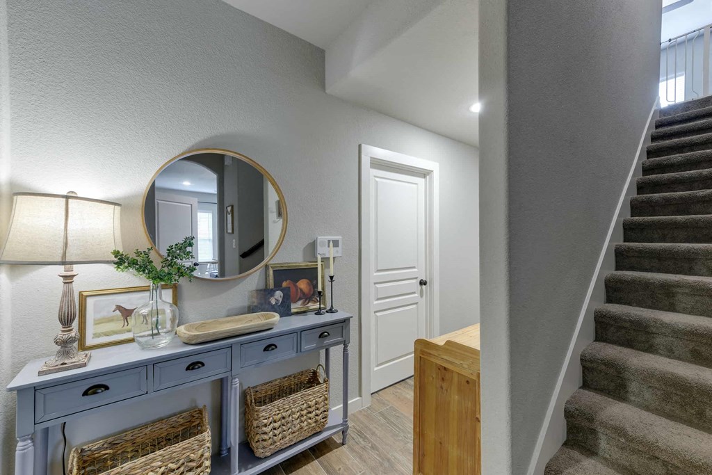 a hallway with stairs and a blue dresser with a mirror