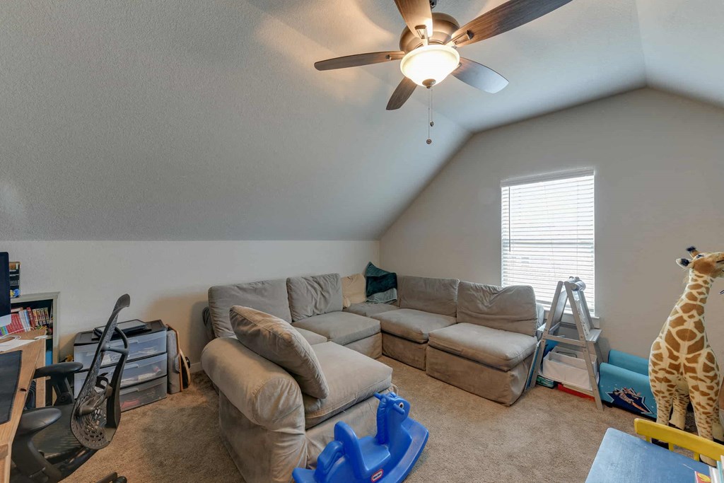the living room has a ceiling fan and couches