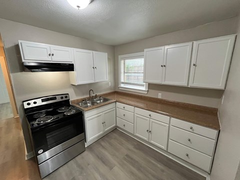 A kitchen with white cabinets and a stove top oven.