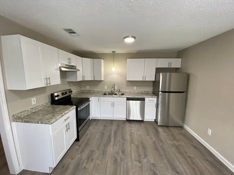 A kitchen with white cabinets and a granite countertop.