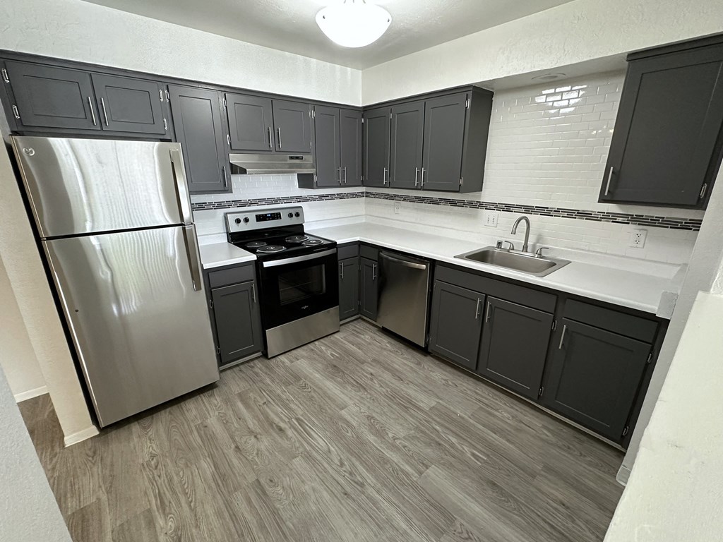 an empty kitchen with black cabinets and stainless steel appliances