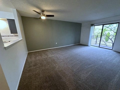 an empty living room with a ceiling fan and a window