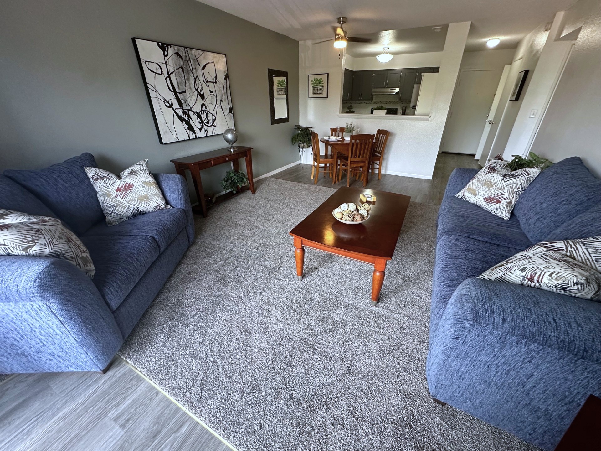 A living room with two blue couches and a wooden coffee table.