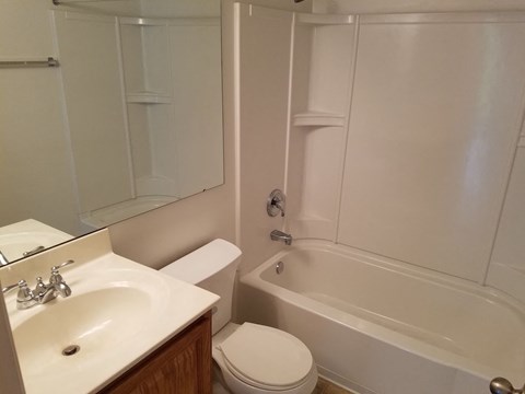 A white bathroom with a sink, toilet and bathtub.
