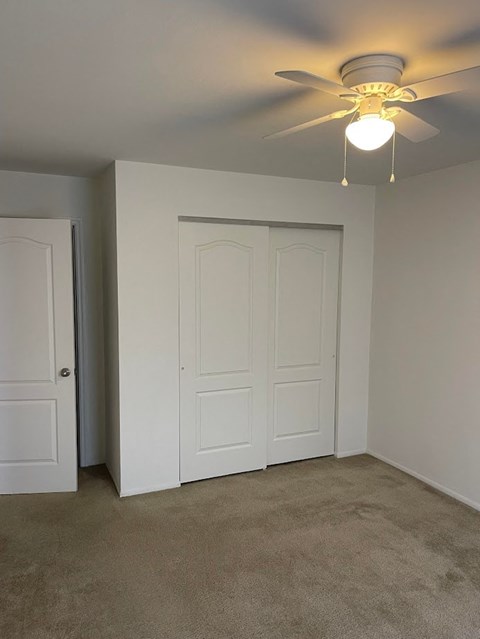 A room with a ceiling fan and two doors.