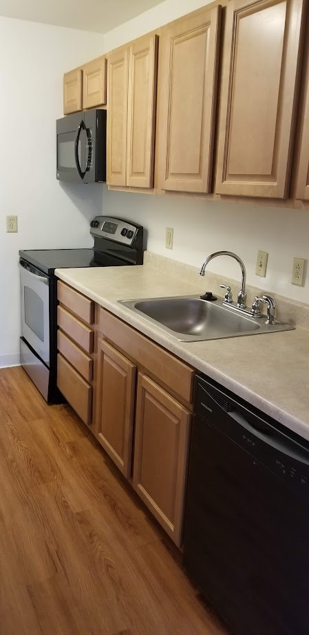 A kitchen with wooden cabinets and black appliances.