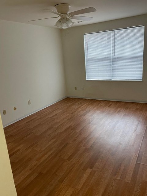 A room with a ceiling fan and wooden flooring.