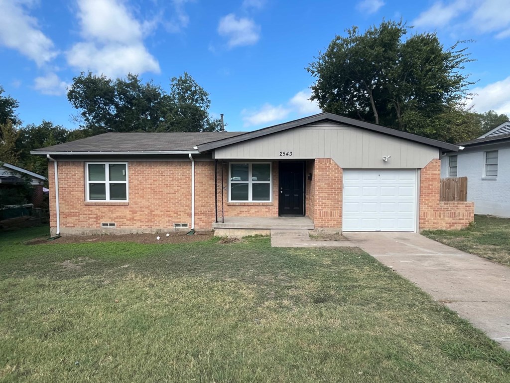 A brick house with a white garage door and a driveway.