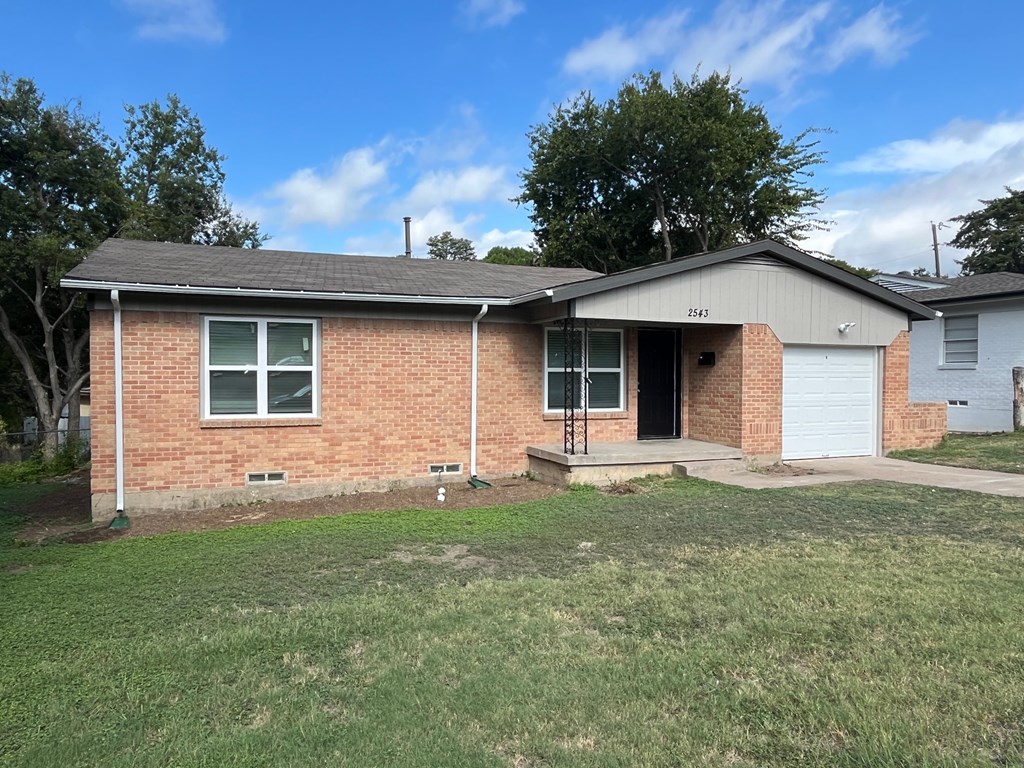 A brick house with a white garage door and a small front yard.