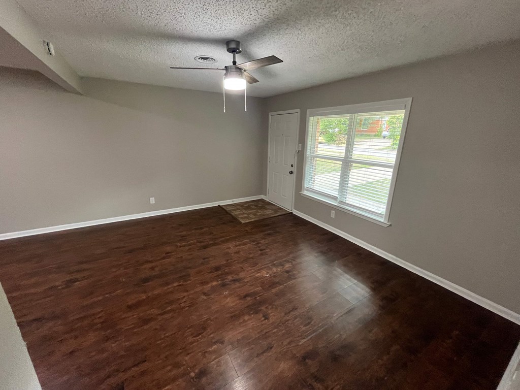 A room with a ceiling fan and wooden flooring.