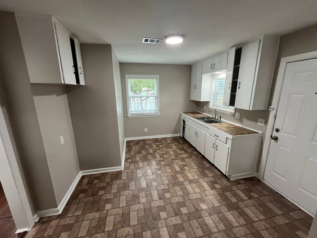A kitchen with brown tiled floors and white cabinets.