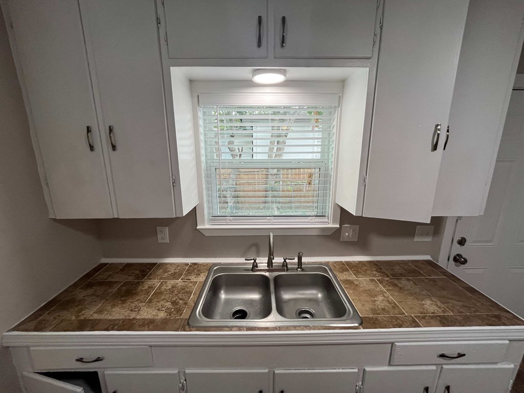 A kitchen with a brown countertop and white cabinets.