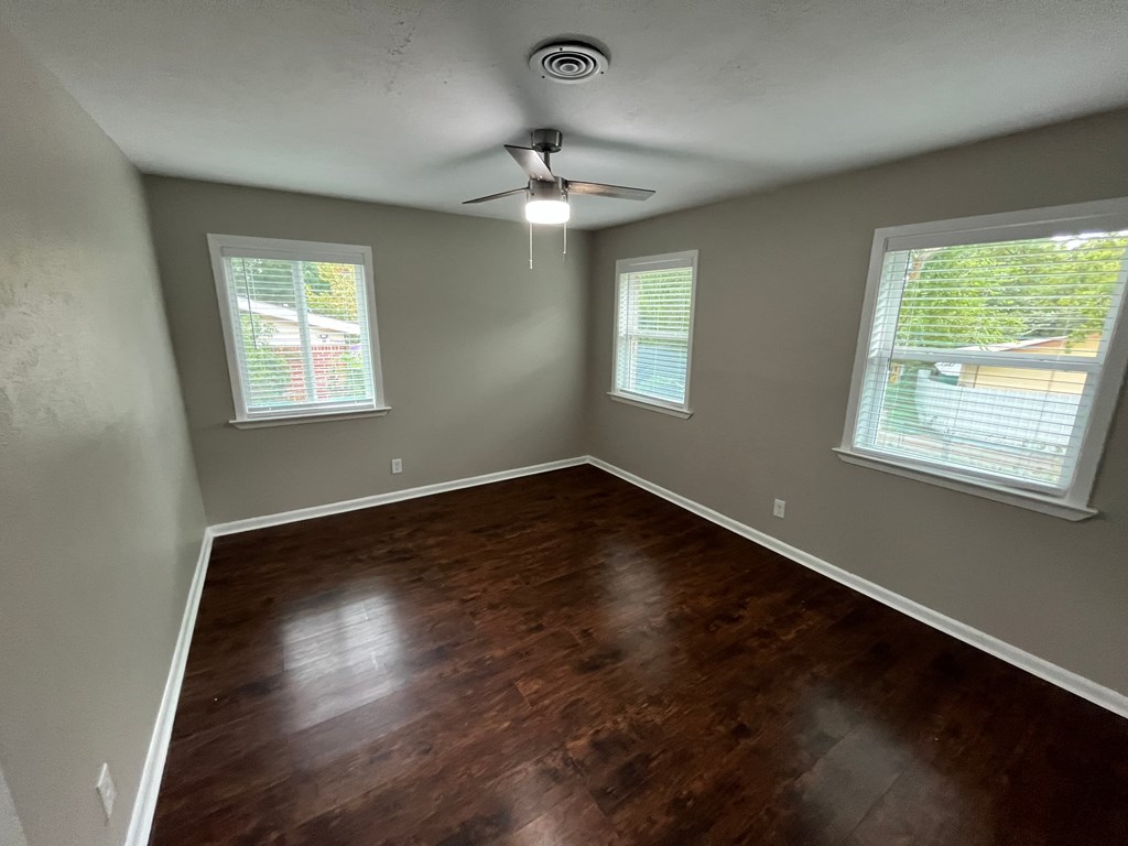 A room with wooden floors and two windows.