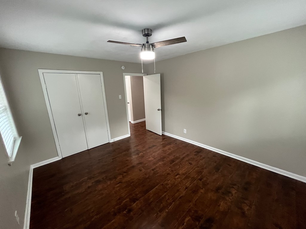 A room with a ceiling fan and wooden flooring.
