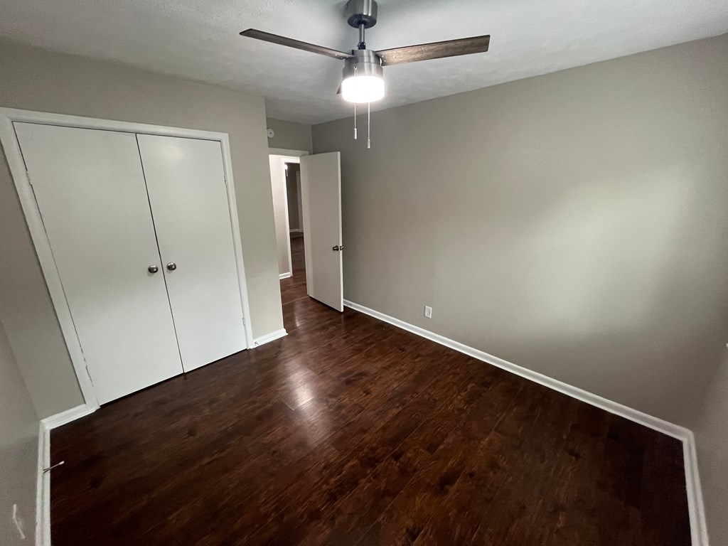 A room with a ceiling fan and wooden floors.