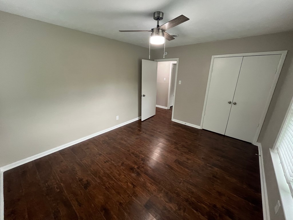 A room with wood flooring and a ceiling fan.