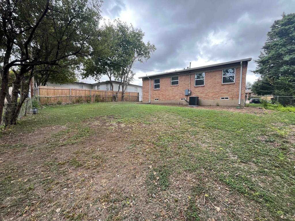 A small brick building sits in a grassy field with trees in the background.