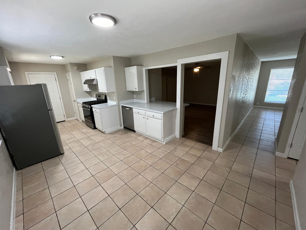 an empty kitchen with tile flooring and white cabinets