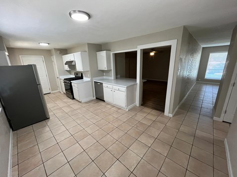 an empty kitchen with tile flooring and white cabinets