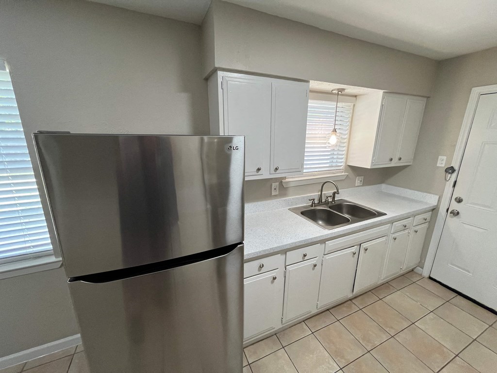 a kitchen with white cabinets and a stainless steel refrigerator