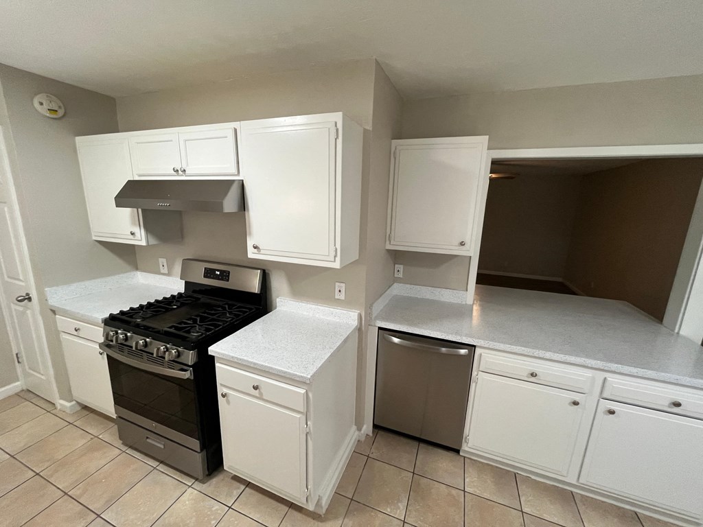 an empty kitchen with white cabinets and a black stove and oven