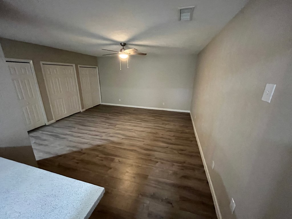 a empty living room with wood floors and a ceiling fan