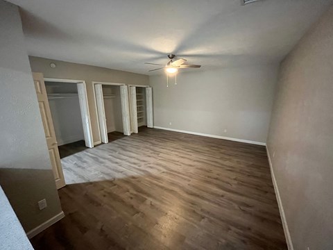 a empty living room with wooden floors and a ceiling fan