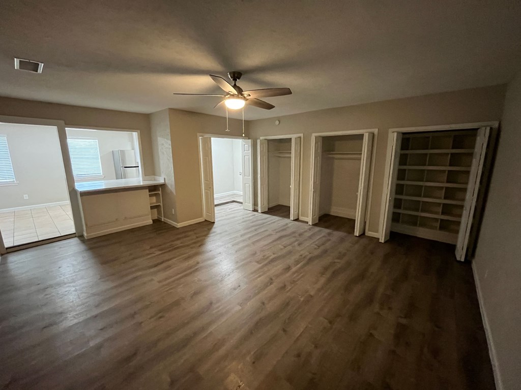 an empty living room with wooden floors and a ceiling fan