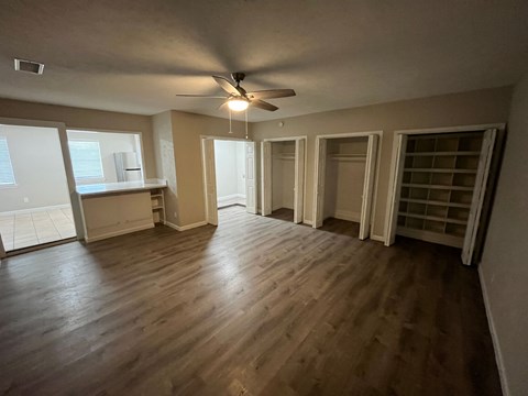 an empty living room with wooden floors and a ceiling fan