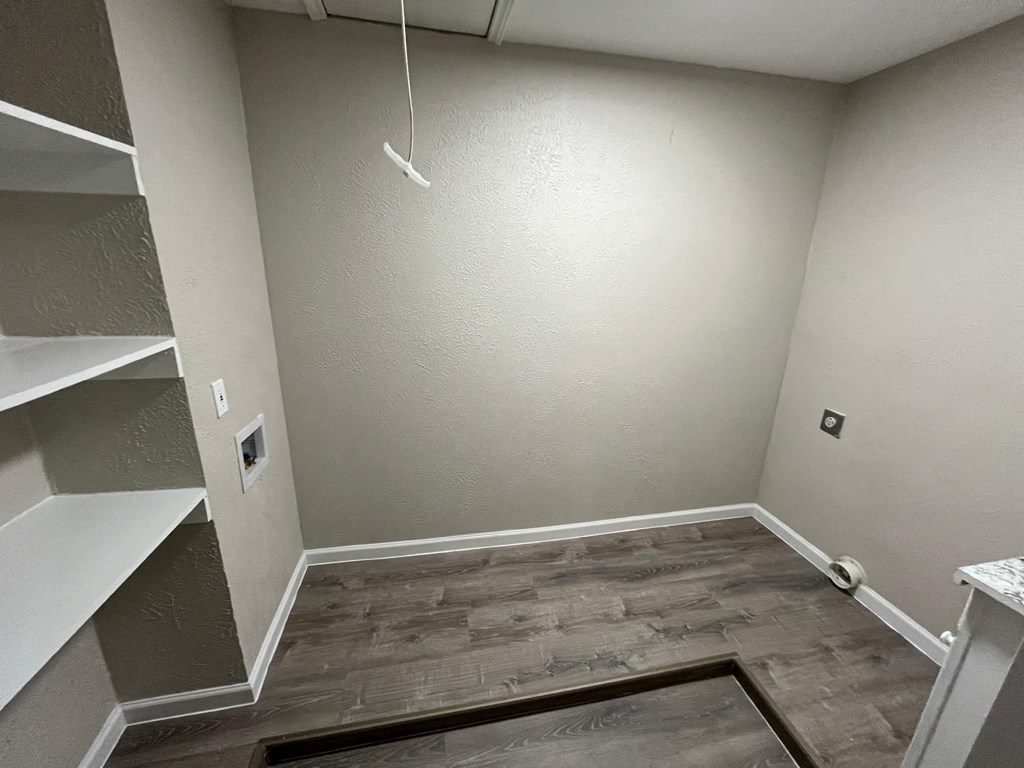 a empty room with wood flooring and a white wall