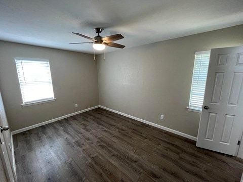 a bedroom with wood flooring and a ceiling fan