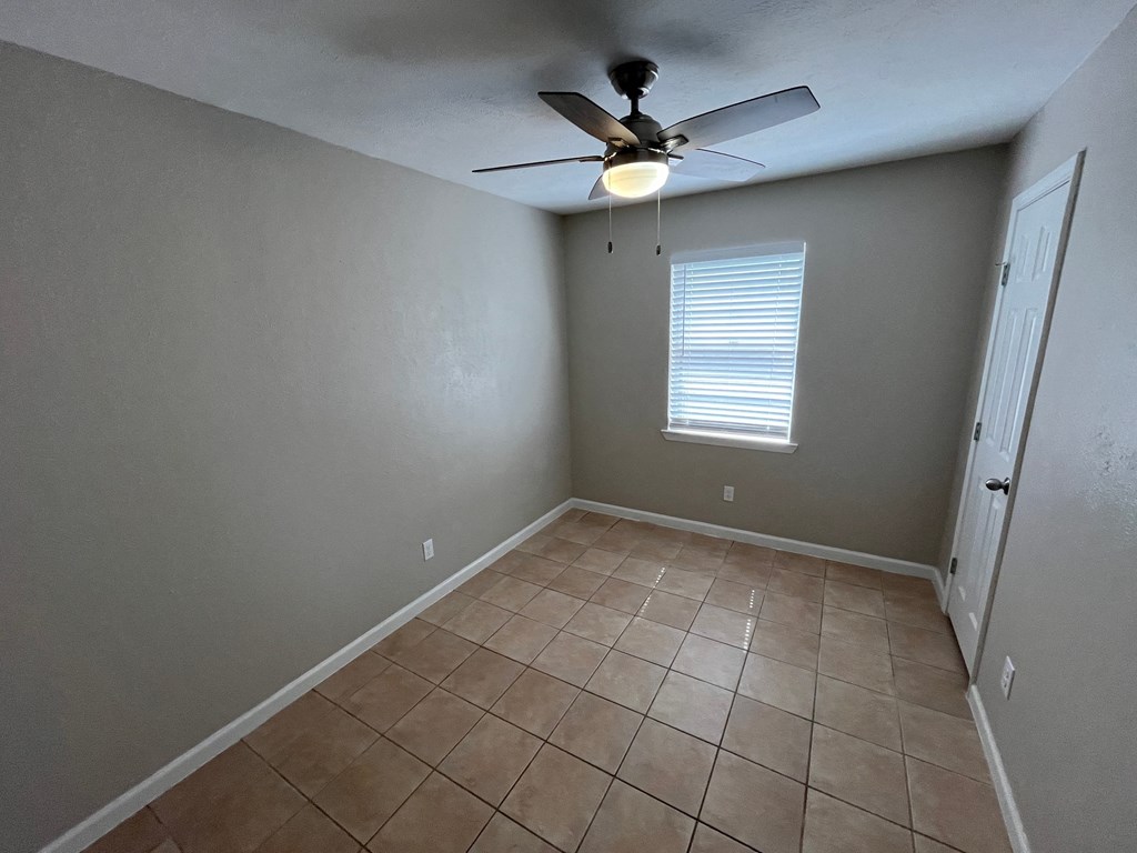 a empty room with a ceiling fan and a tiled floor