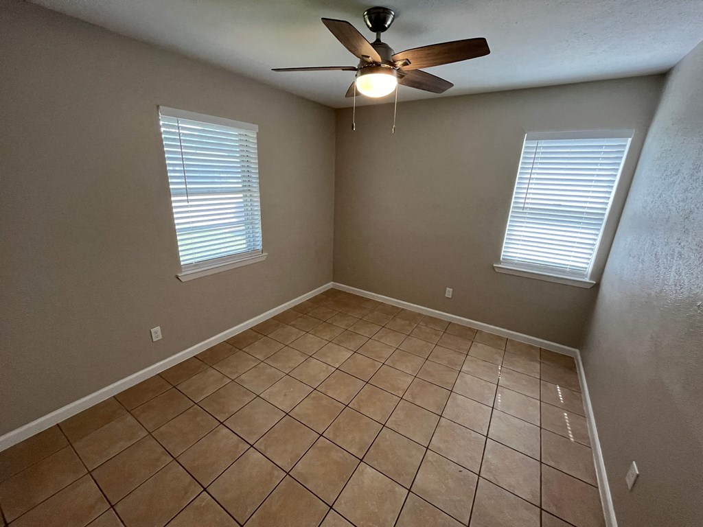 a empty room with a ceiling fan and a tiled floor